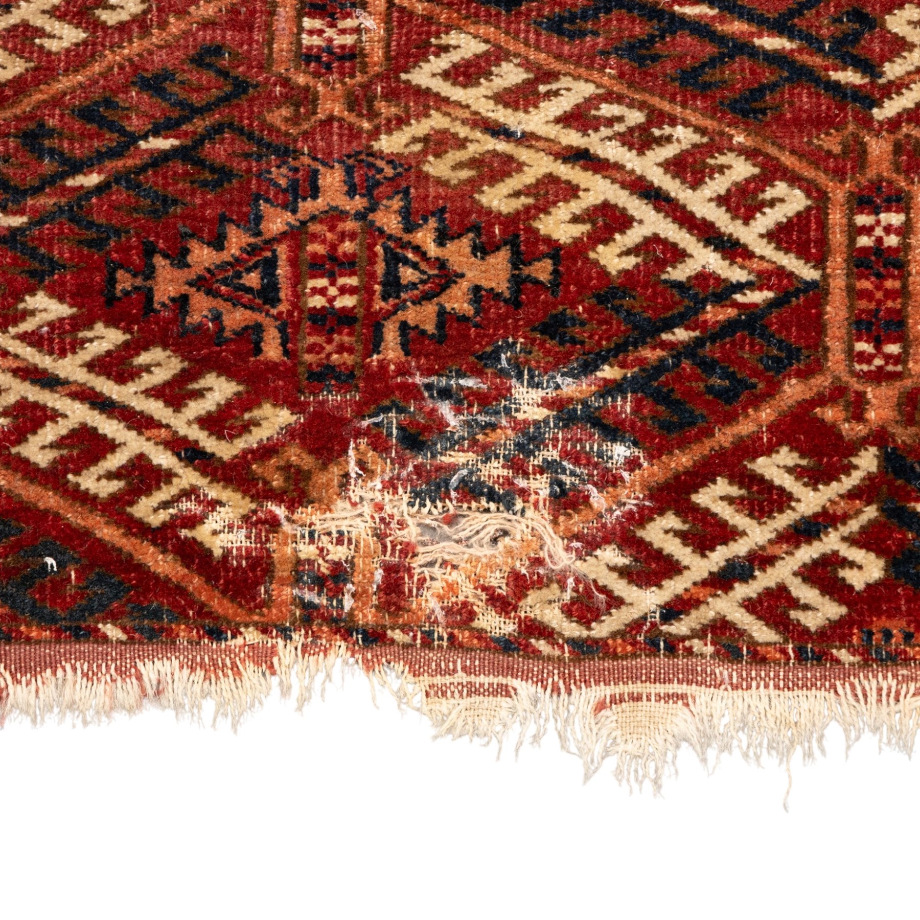Persian Bokhara crimson ground rug, the field decorated with five rows of repeating Gul motifs with interspersed geometric design, enclosed by a guard band of further geometric-style Gul designs comprised of hook motifs