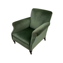Early 20th century upholstered armchair, deep seat with curved arms, on turned mahogany feet