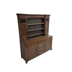 George III oak dresser, projecting cornice over three tier plate rack flanked by reeded uprights and two cupboards, enclosed by slatted and panelled doors above small drawers, the lower section fitted with six drawers and two cupboards, on bracket feet