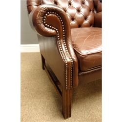  Georgian style mahogany framed high wingback club armchair, upholstered in deep buttoned brown leather, on square moulded supports with stretchers, W83cm, H114cm, D93cm  