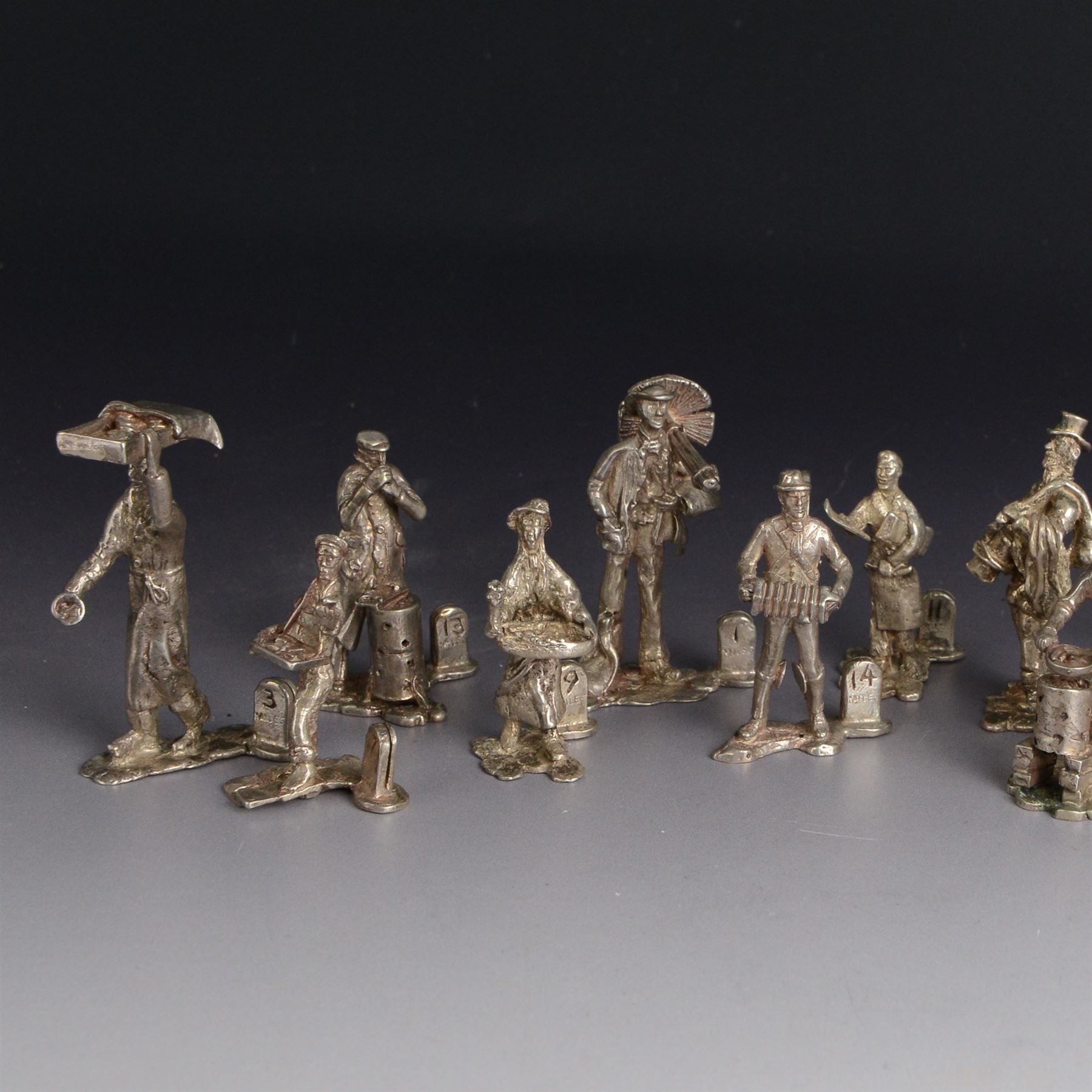 Set of twelve silver place card holders from the 'Cries of London' series, each depicting traditional London street traders, hallmarked Thomas Charles Jarvis, London 1975, tallest H6.5cm