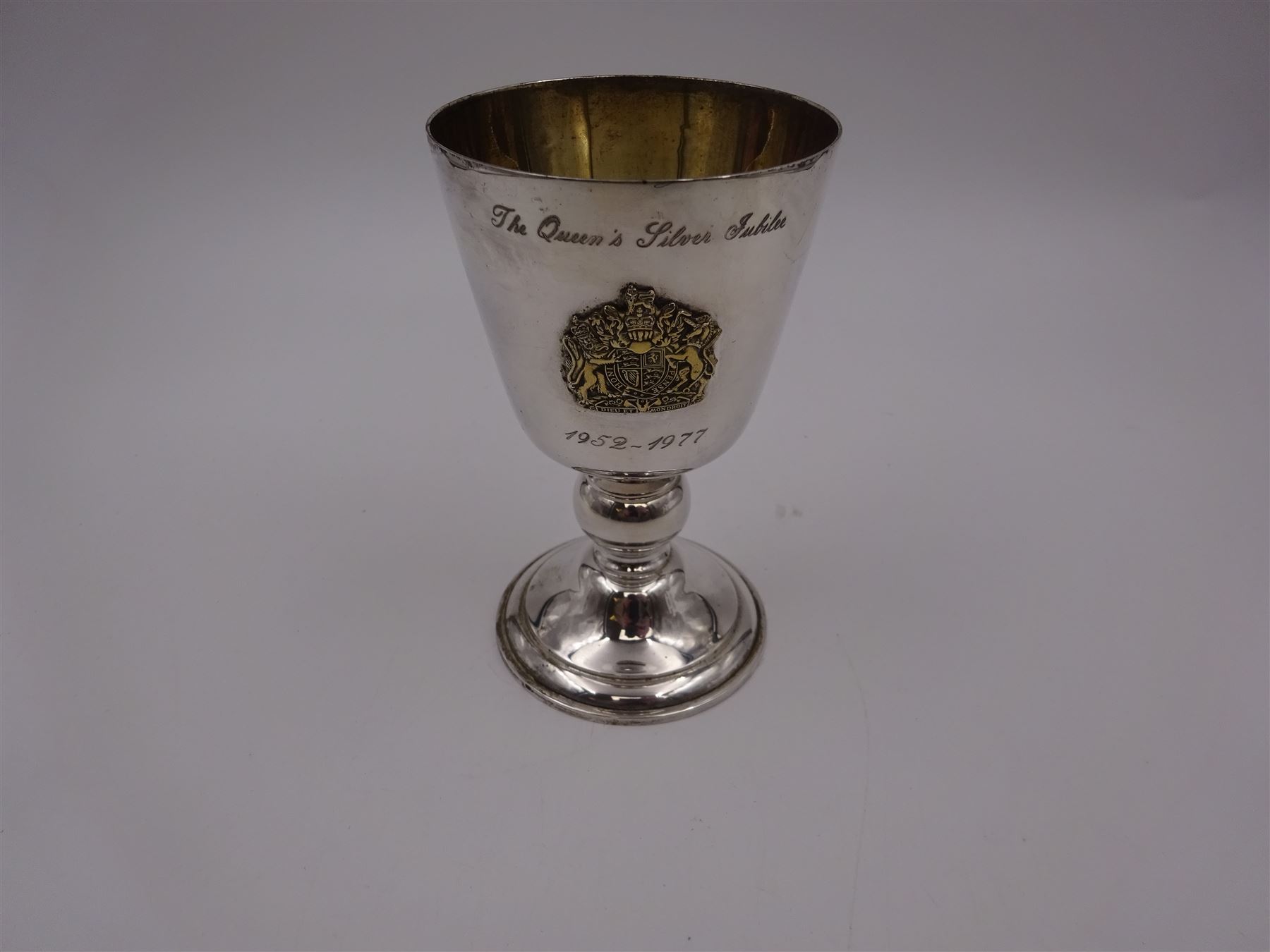 Modern limited edition silver goblet, commemorating Queen Elizabeth II silver jubilee, of plain form with gilded interior, applied Royal coat of arms to body and engraved 'The Queen's Silver Jubilee 1952-1977' upon knopped stem and circular spreading foot, limited edition no. 320/1000, hallmarked A T Cannon Ltd, Sheffield 1977, boxed with certificate, goblet H12.8cm