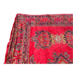 Early 20th century Western Anatolia Turkish Oushak crimson ground carpet, the field decorated with rows of Herati and Palmette medallions, the main border decorated with stylised flower head motifs within guard stripes