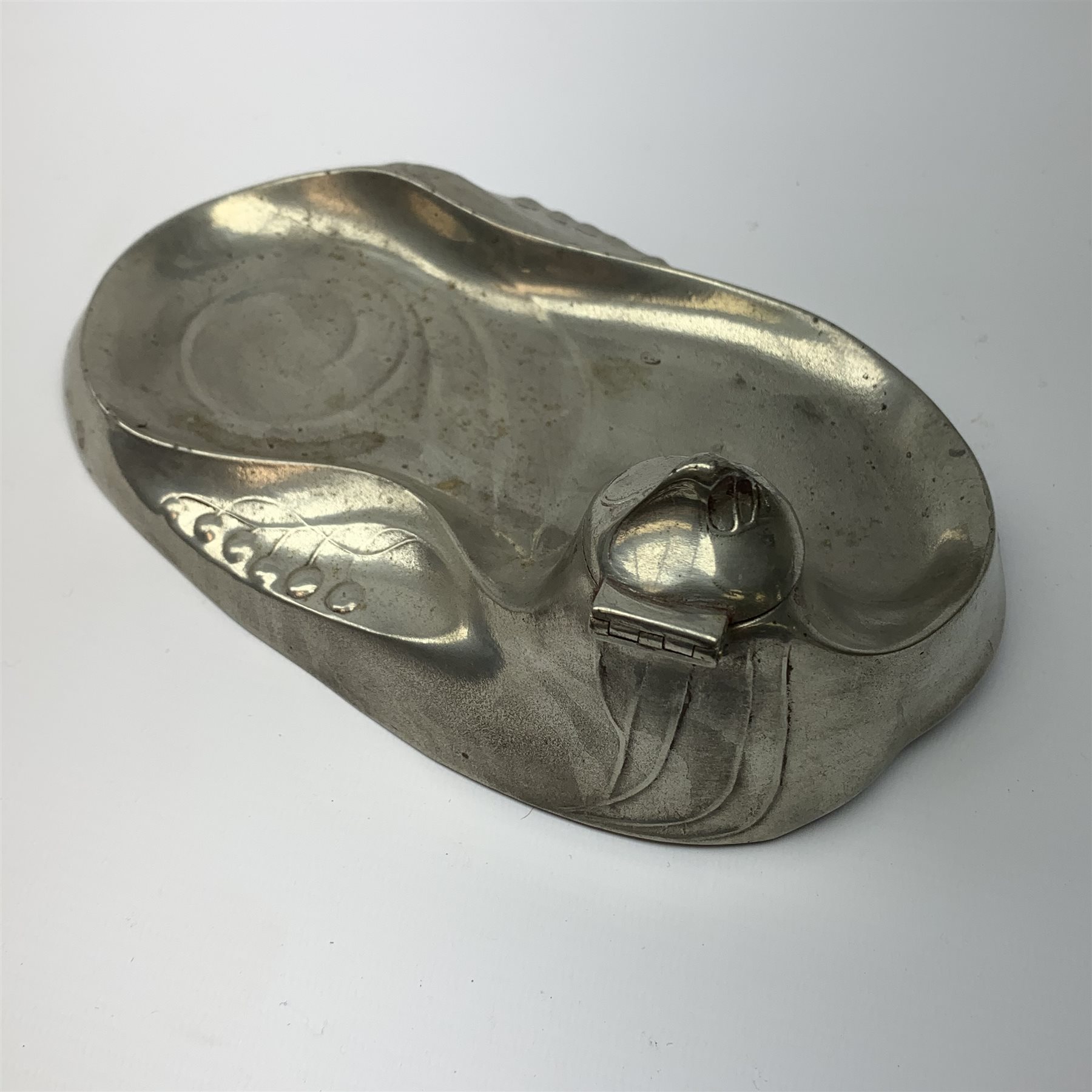 A Kayserzinn Art Nouveau pewter ink stand and pen tray, designed by Hugo Leven, of shaped oval form detailed with stylised tendrils, the hinged inkwell cover opening to reveal an amethyst glass liner, marked beneath Kayserzinn 4438, L21cm.