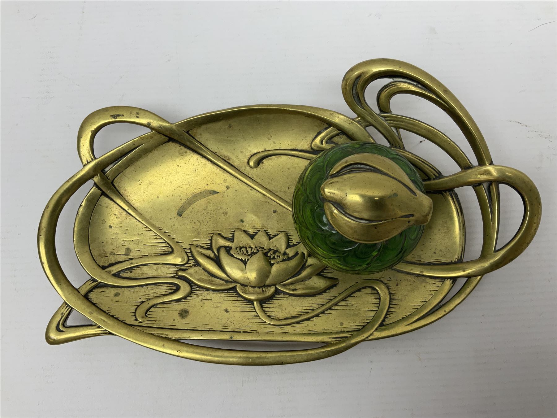 Art Nouveau Geschutzt brass desk stand, with stylised whiplash relief decoration, with removable Loetz style green glass inkwell, stamped to the base, H8cm