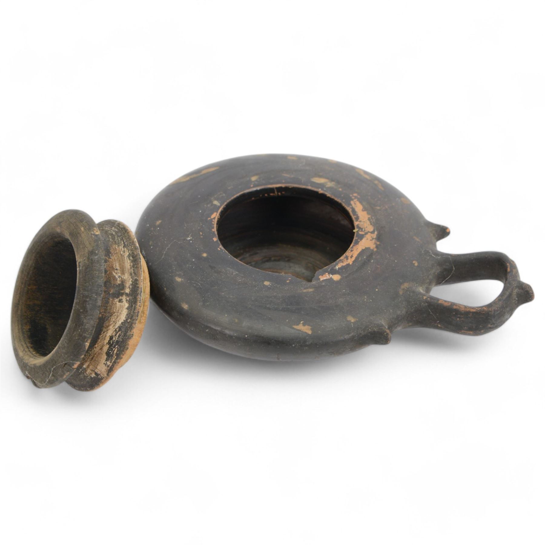 Etruscan terracotta oil lamp, with black glaze, flat loop handle and laurel leaf border, the opening with later turned wooden collar, signed to base 'repaired by one James Naysmith 1887', H7cm 