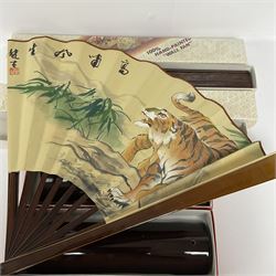 Two Oriental hand-painted fans, decorated with birds and a tiger, with stands (2)