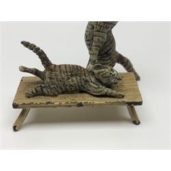 After Bergmann, two cold painted bronze figures, the first modelled as two cats on a bench hugging, the second a cat caning a kitten