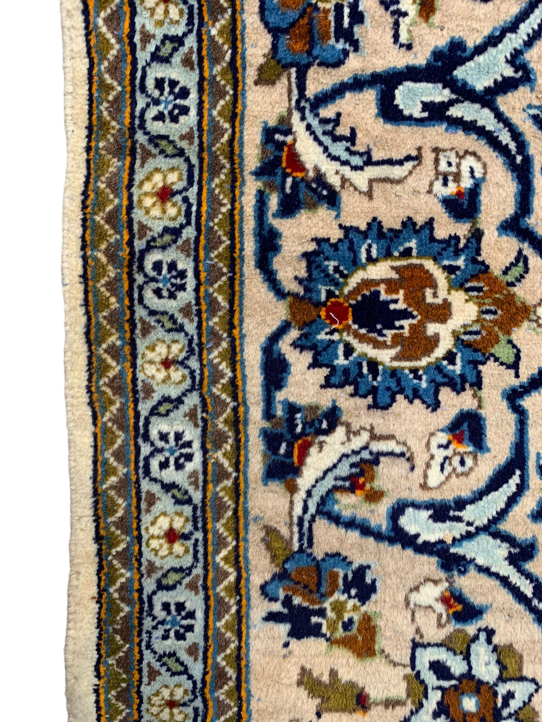 Persian Kashan ivory ground rug, the field decorated with stylised plant motifs and interlacing leafy branches, scrolling border decorated with further plant motifs, floral design guard bands  