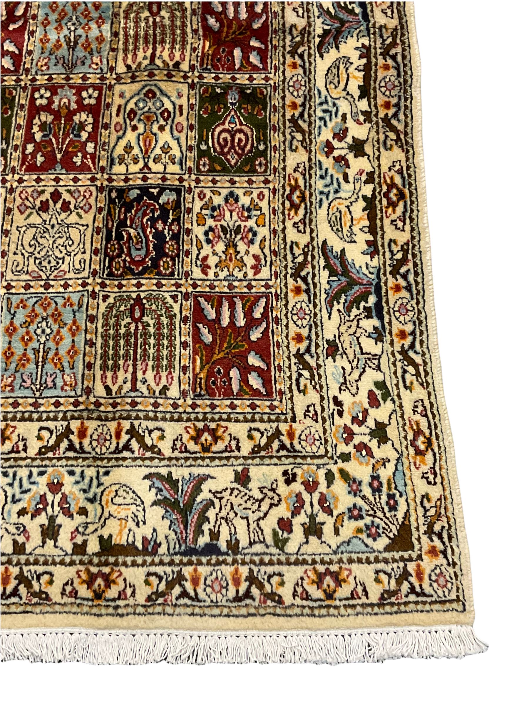 Persian Heriz design rug, ivory ground with rectangular panels each depicting garden scenes of tree of life, plants and Boteh motifs, the guarded border decorated with wildlife and bird scenes