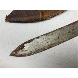 Mandingo sword, the 63cm plain curving steel blade marked with a horses head and the initials G.S.; leather covered grip with metal ribbed spherical pommel; in decorative leather leaf scabbard mounted with tassels and roundels L84cm overall; and a North African flyssa sword in poor condition with wooden scabbard (2)