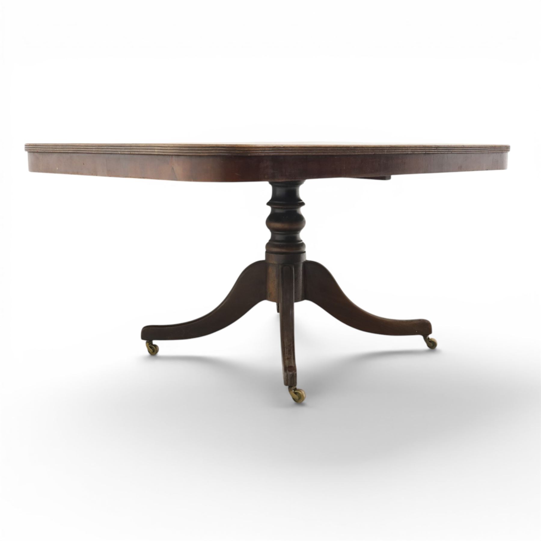 Regency mahogany tilt-top dining table, crossbanded rounded rectangular top, raised on a splayed base, terminating in brass castors