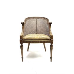 Early 20th century walnut Bergère chair, moulded and shaped frame terminating in rams head, cane woven back meets patterned upholstered seat, raised on leaf carved and fluted supports 