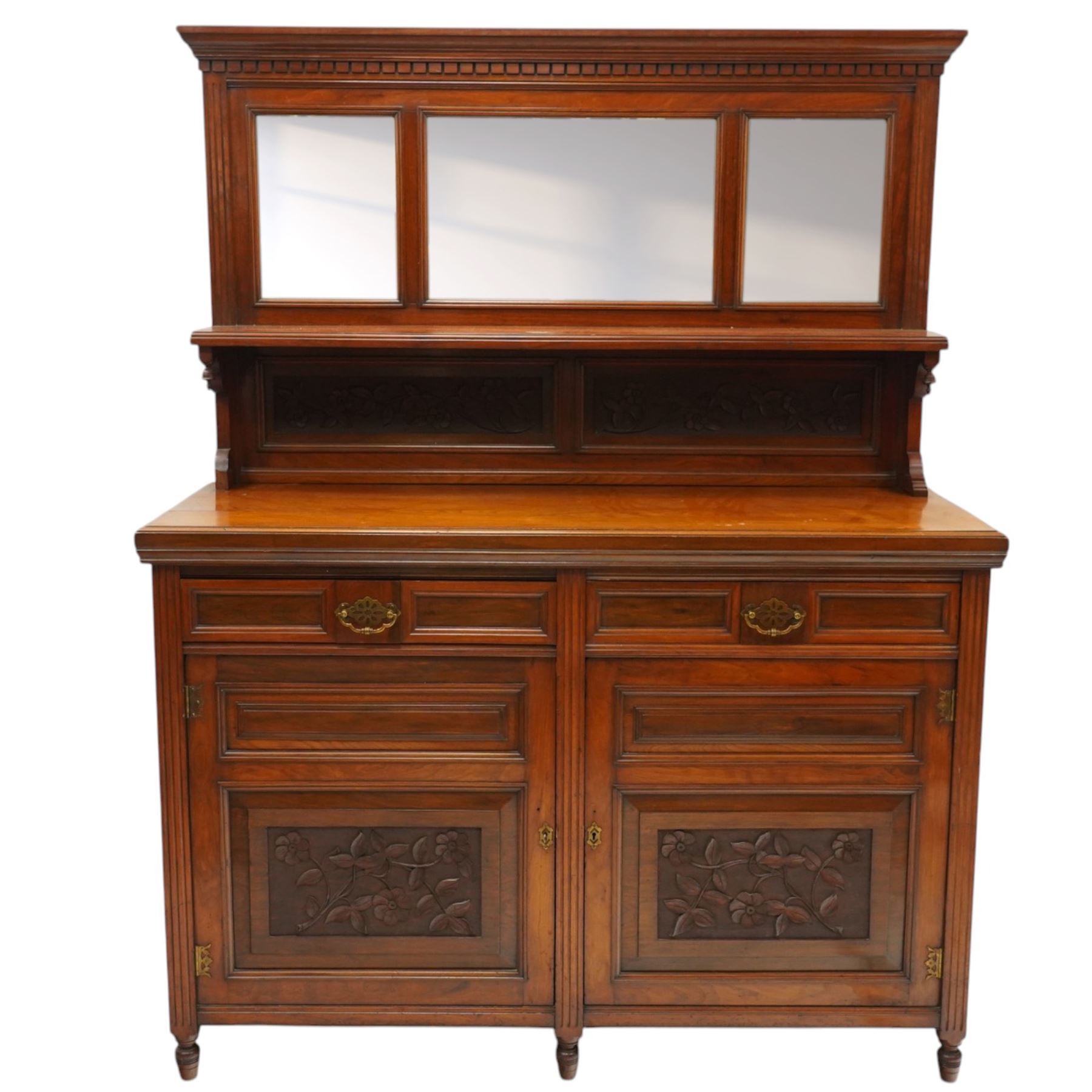 Late Victorian mahogany mirrored back sideboard, the mirror back with three bevelled mirror plates above a single shelf, rectangular moulded top over two frieze drawers with brass handles, above a twin panelled cupboard, carved recessed panels decorated with flowers and foliage, fluted uprights, raised on turned feet