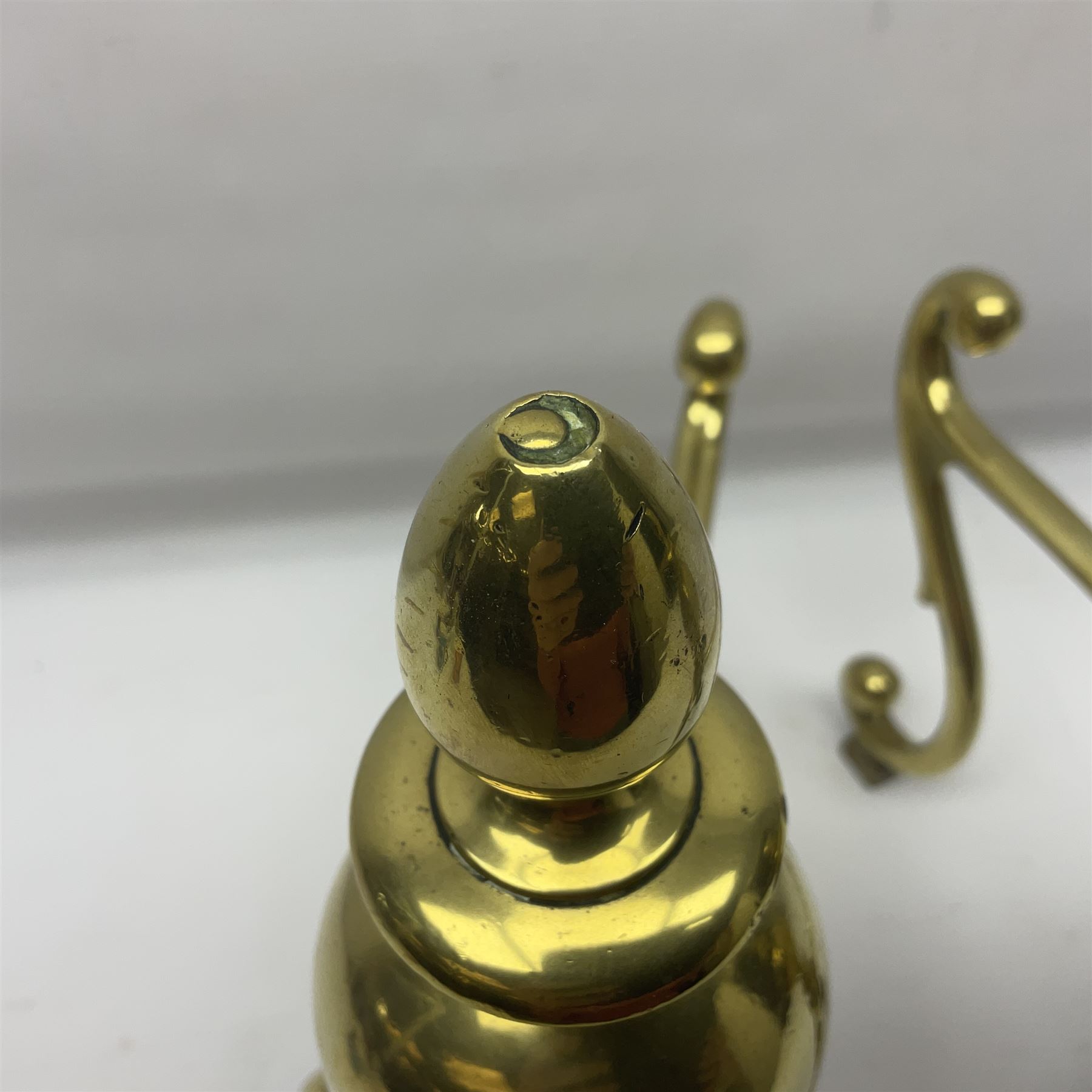 Pair of early 20th century brass fire dogs, each with sphere and urn finial, upon a scrolling base, H38cm