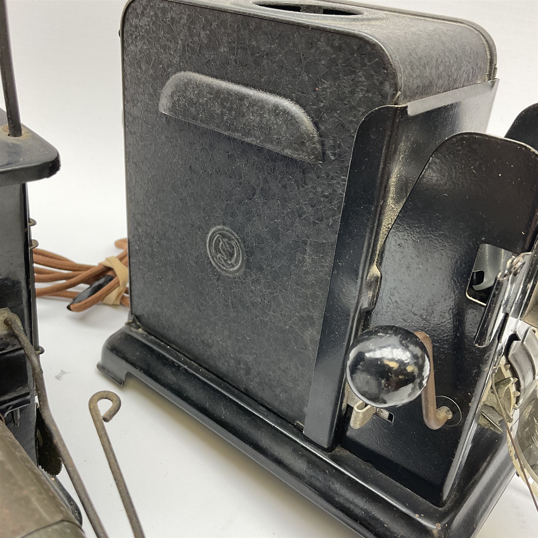 Early 20th century tinplate combined magic lantern and 35mm cinematograph projector, hand-cranked, with electric bayonet lamp, fitted with film reels, L35cm overall, and a similar projector by Gebruder Bing Nuremberg with spirit lamp (glass chimney a/f) L22cm, with two reels of film 