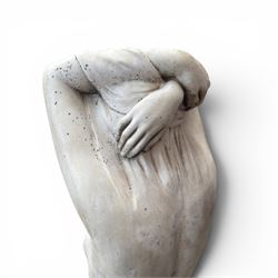 20th century composite stone garden figure, modelled as a kneeling nude female with arms raised behind her head, mounted on an integral cushion, the squared ogee pedestal moulded with acanthus leaves and flower heads, in a white painted and weathered finish