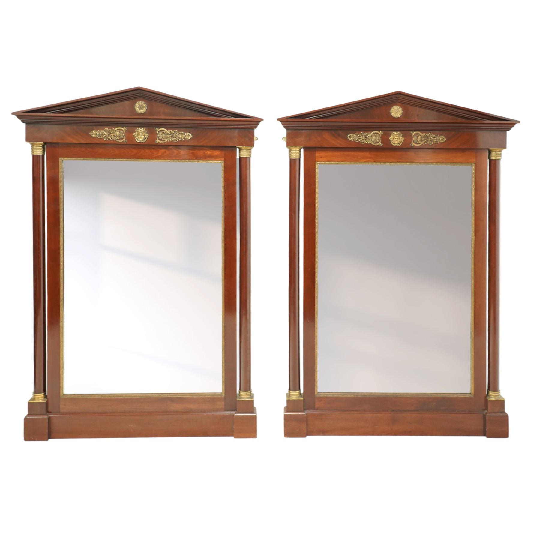 Rare pair of French Second-Empire neoclassical style mahogany mirrors with ormolu mounts, architectural pediment with central ormolu patera above flame mahogany frieze with honeysuckle flower and caryatid mounts, the frame with ormolu beading and bevelled mirror plates, flanked by turned columns with ormolu mounts above a reverse breakfront base, circa 1870