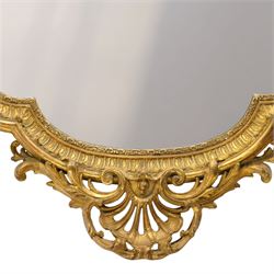 Victorian giltwood and gesso framed ornate wall mirror, the protruding cartouche pediment decorated with extending scrolls of acanthi and flower heads, with scrolled foliage corners flanking a carved slip with further gadrooned scroll decoration, contained a shaped rectangular bevelled plate, over a pierced and scrolling scallop shell terminal