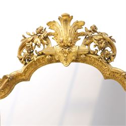 Victorian giltwood and gesso framed ornate wall mirror, the protruding cartouche pediment decorated with extending scrolls of acanthi and flower heads, with scrolled foliage corners flanking a carved slip with further gadrooned scroll decoration, contained a shaped rectangular bevelled plate, over a pierced and scrolling scallop shell terminal