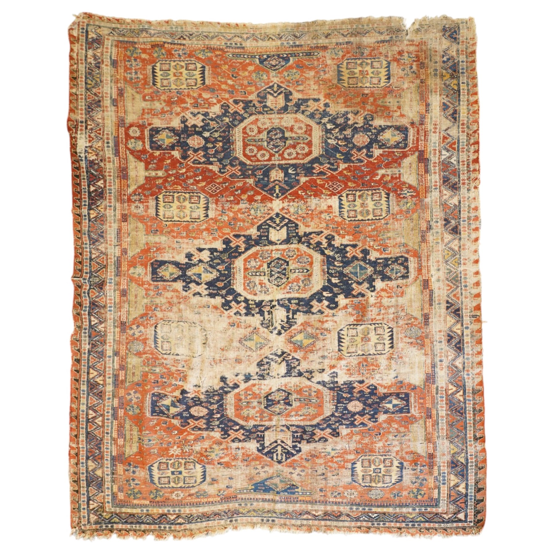 Antique Caucasian crimson ground carpet. the field decorated with three geometric indigo medallions with surrounding geometric motifs and guard lines