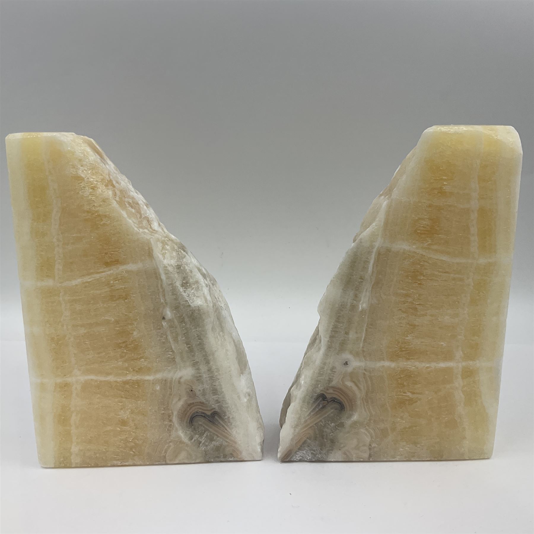 Pair of honey onyx bookends of rectangular form with polished to three sides with a raw outer edge, H18cm 