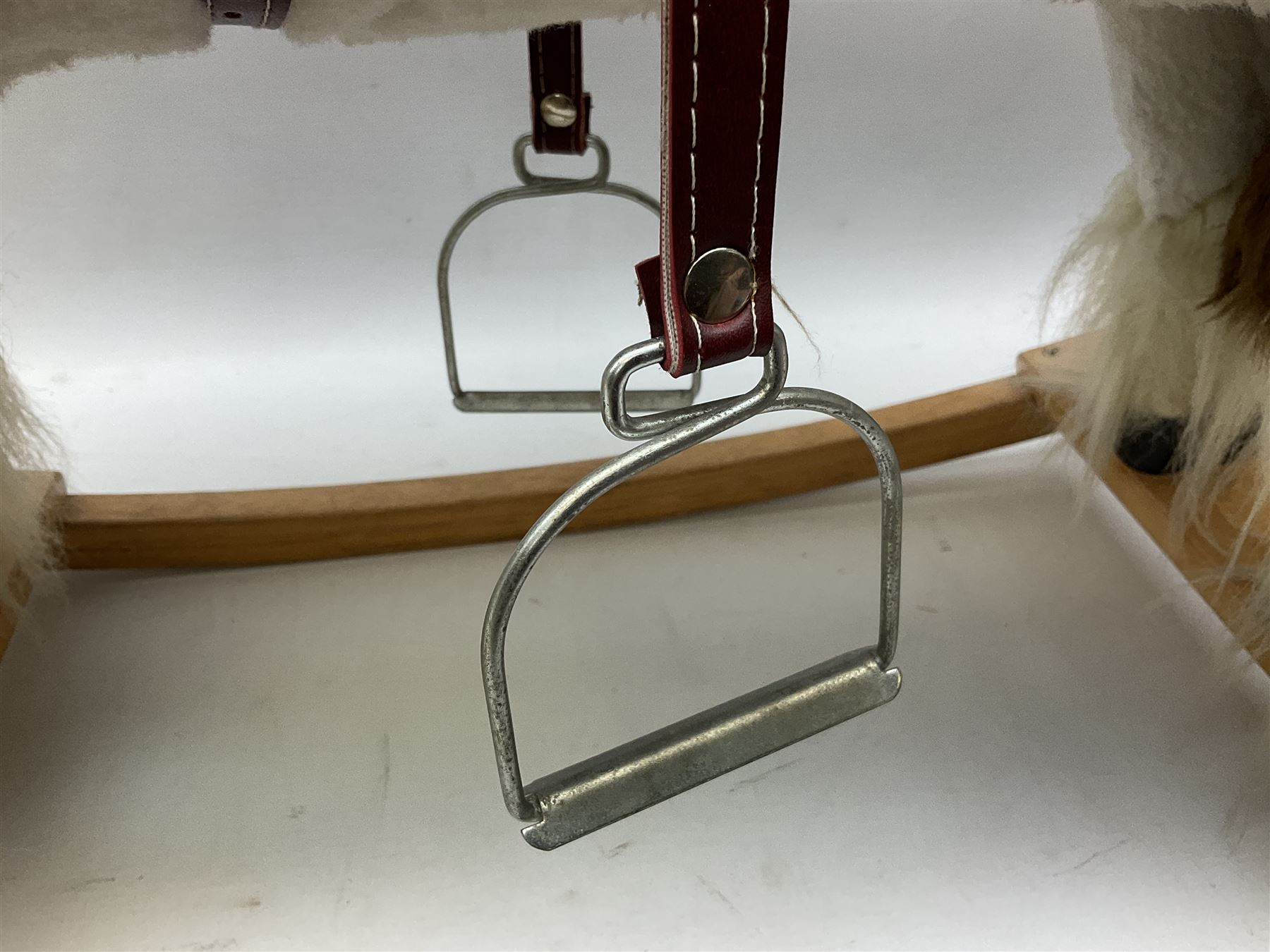 Modern plush covered rocking horse with inset eyes, simulated leather bridle and saddle with metal stirrups, on curving wooden rockers L94cm H64cm