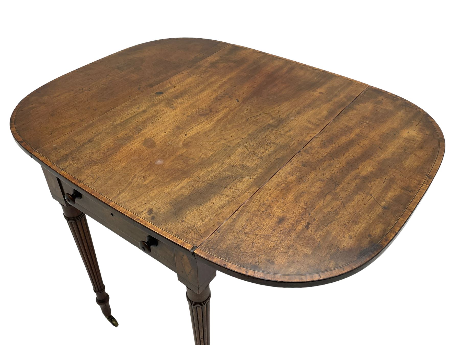 George III mahogany Pembroke table, drop-leaf oval top with satinwood band, fitted with single end drawer, inlaid with satinwood lozenge motifs, on turned and reeded supports with brass cups and castors