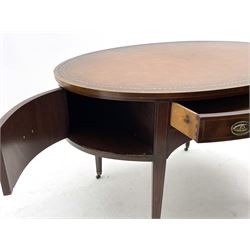 Georgian style mahogany and yew wood banded oval library writing table, the top with tooled and gilt brown leather inset, fitted with drawer, two cupboards and shelf, raised on square tapering supports terminating at brass castors, boxwood stringing