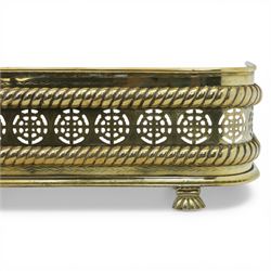 20th century pierced brass fender, with pierced roundels between oblique gadrooned borders, upon three paw feet