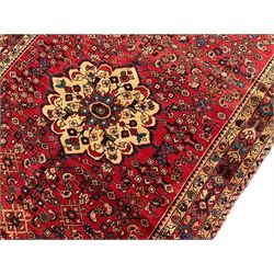 North West Persian Malayer Kelleh crimson ground rug, the central ivory medallion within a field decorated with all over Herati motifs, the guarder border with repeating stylised plant patterns and the adjacent bands with scrolling flower heads 