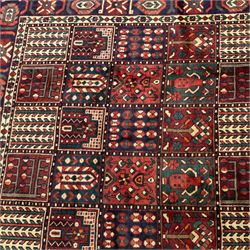 Bakhtiari wool rug, compartmented garden design field with panels of stylised trees, flowers and geometric motifs, enclosed by dark blue main border with repeating floral medallions and guard stripes