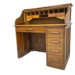 Early 20th century oak roll-top desk, the tambour enclosing pigeon holes and small drawers, the base fitted with slide, a single long drawer and three smaller drawers
