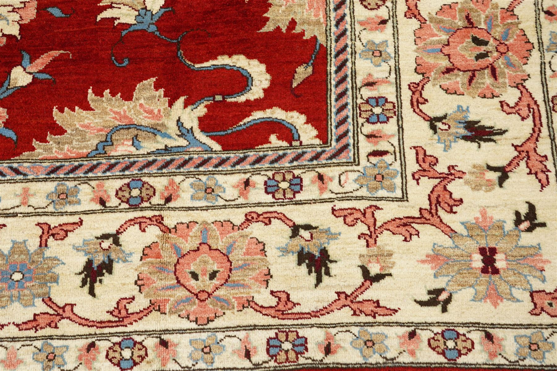 West Persian Sarough hand-knotted carpet, rich madder red field, decorated with stylized palmettes angular vinery and floral sprays within multiple borders of ivory ground and scrolling foliate decoration, with cotton fringe ends 