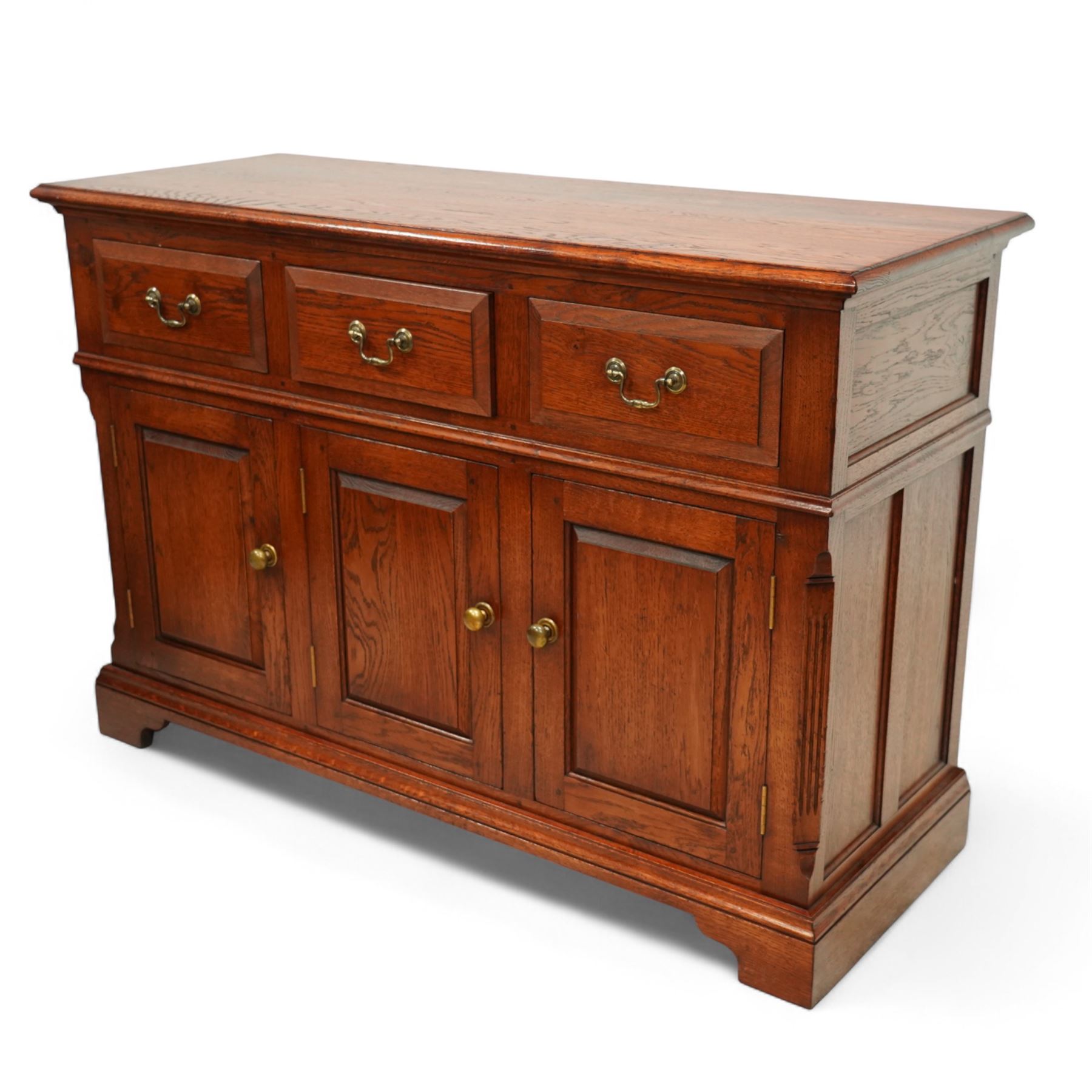 20th-century oak side cabinet, rectangular top above an arrangement of three drawers and three panelled cupboard doors, fitted with brass knobs, raised on bracket feet  