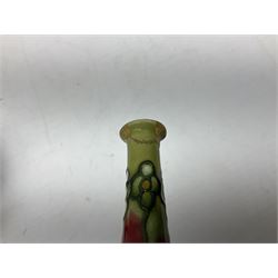 Three Minton Secessionist vases, with tube-lined stylised flower decoration, two upon a red ground and third upon a purple ground, all with printed mark to base 'Minton Ltd, No. 33', H13cm