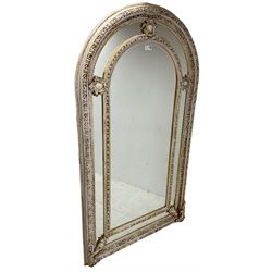Large painted and gilt arched wall mirror, the frame decorated with scrolling leafy branches, central bevelled mirror mirror surrounded by plain panels, decorated with cartouche mounts 