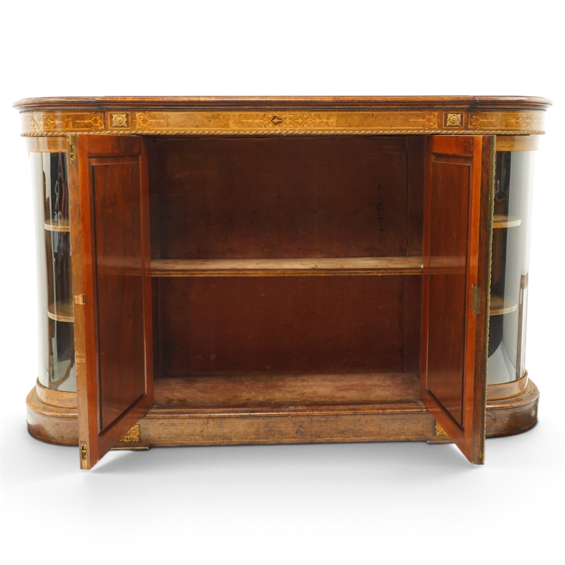Large fine Victorian figured and burr walnut credenza, the breakfront D-shaped top with moulded edge, over an ornate frieze with inlaid Aesthetic Movement scrolling and geometric ornament, applied with gilt-metal ribbon-twist moulding and mounts, the central panelled doors profusely inlaid with scrolling foliate motifs and stringing, flanked by gilt-metal cartouche and scrolling acanthus corbel mounts, with flanking glazed bow-front side doors, on skirted base with further gilt metal foliate mounts