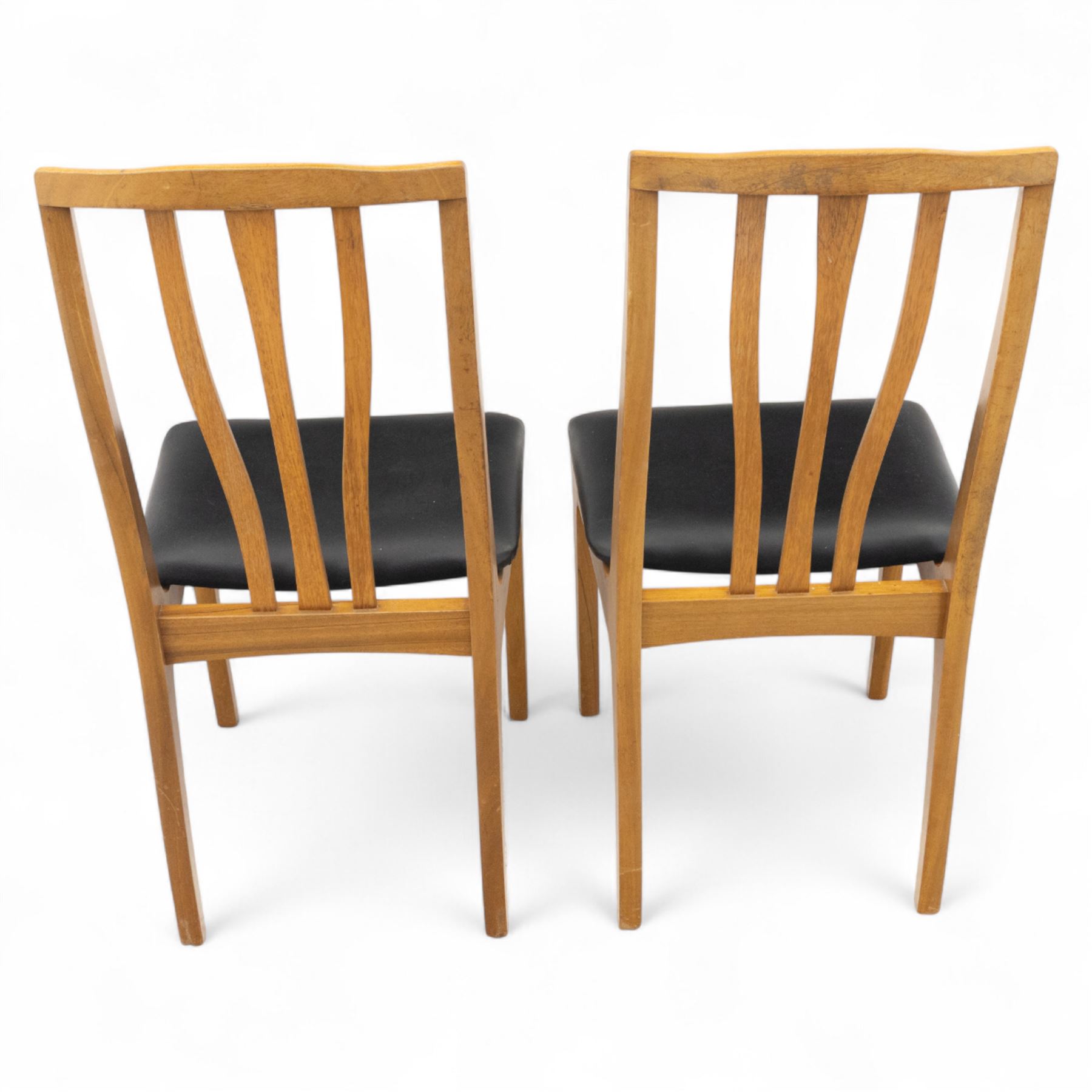 Sutcliffe of Todmorden - mid 20th century ‘S-Form’ teak dining table and chairs, the circular storable extending table with plain veneered top on tapered supports, together with matching dining chairs upholstered in black vinyl, with curved slat backs and shaped front supports, reflecting the sleek organic styling characteristic of 1960s British modern furniture design (Chairs H 93cm, W 46cm, D 46cm) (Extended 168cm)