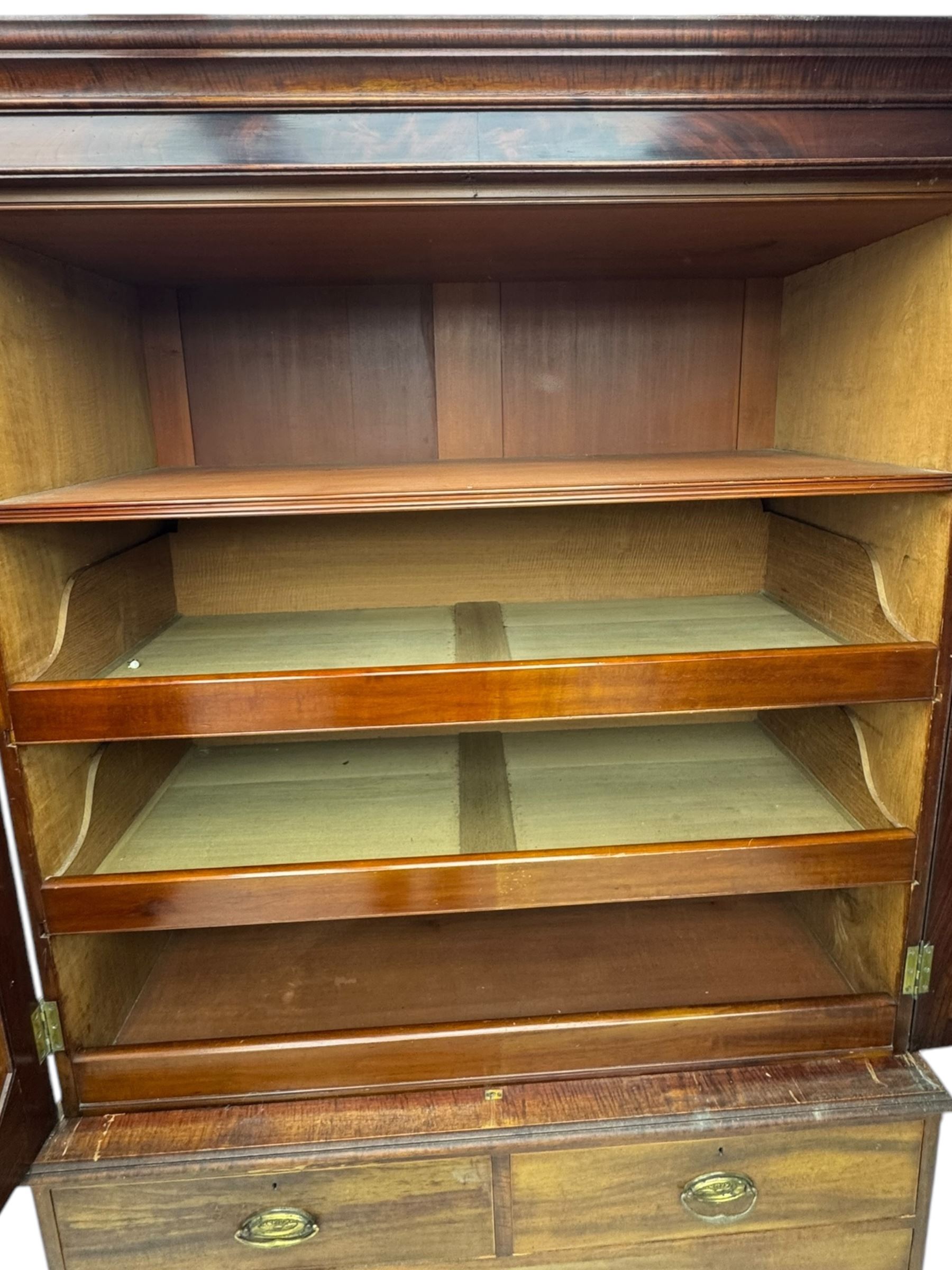 George III mahogany linen press cupboard, projecting moulded cornice over two panelled doors, the interior fitted with two slides and shelf, two short and two long drawers below, shaped apron over bracket feet 