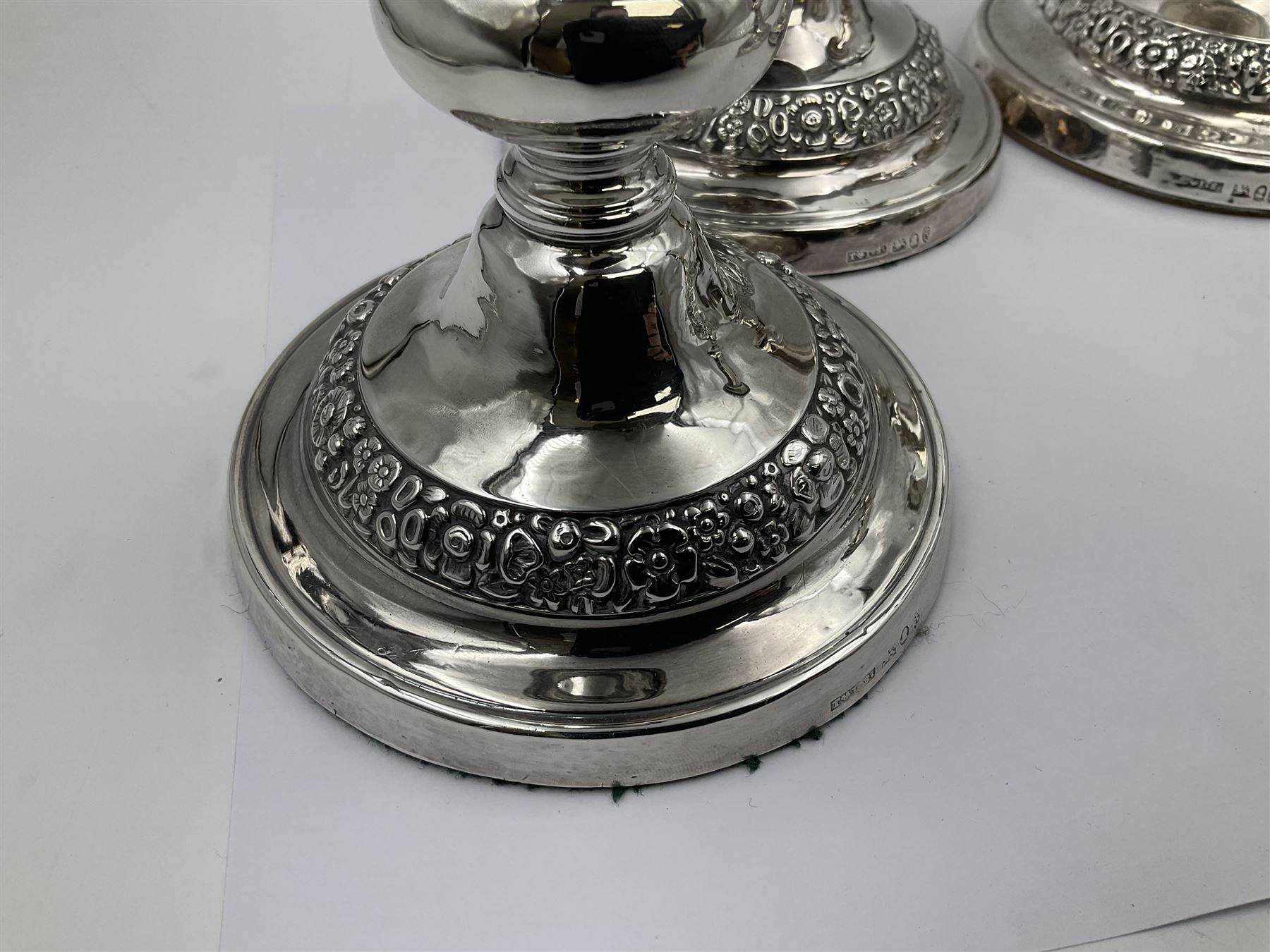 Four George III silver candlesticks, each upon knopped stem and weighted circular stepped foot, the foot and removable sconce repousse decorated with a band of flower heads, hallmarked to sconce and foot Thomas & John Settle, Sheffield 1820, H17.5cm