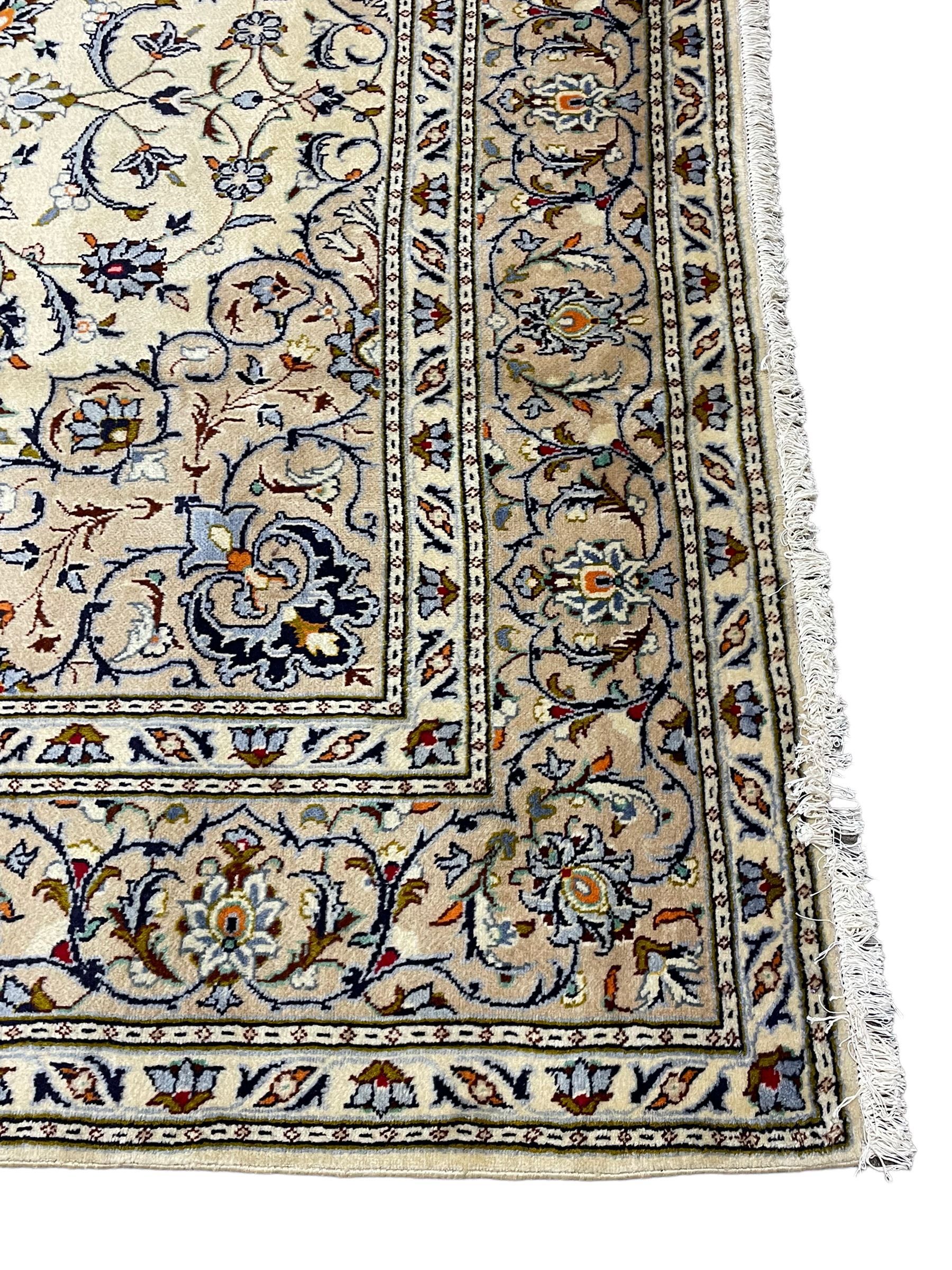 Persian Kashan ivory ground carpet, decorated all-over with interlacing foliate and stylised plant motifs, central scrolling medallion and matching spandrels, the guarded border decorated with repeating palmettes