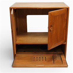Ercol - elm television cabinet, rectangular top with chamfered edges, fitted with a pair of fielded panel cupboard doors with recessed oval pulls, opening to reveal an adjustable shelf and open back for cables, the lower section with drop-front compartment fitted with record slots and wire dividers, raised on concealed castors