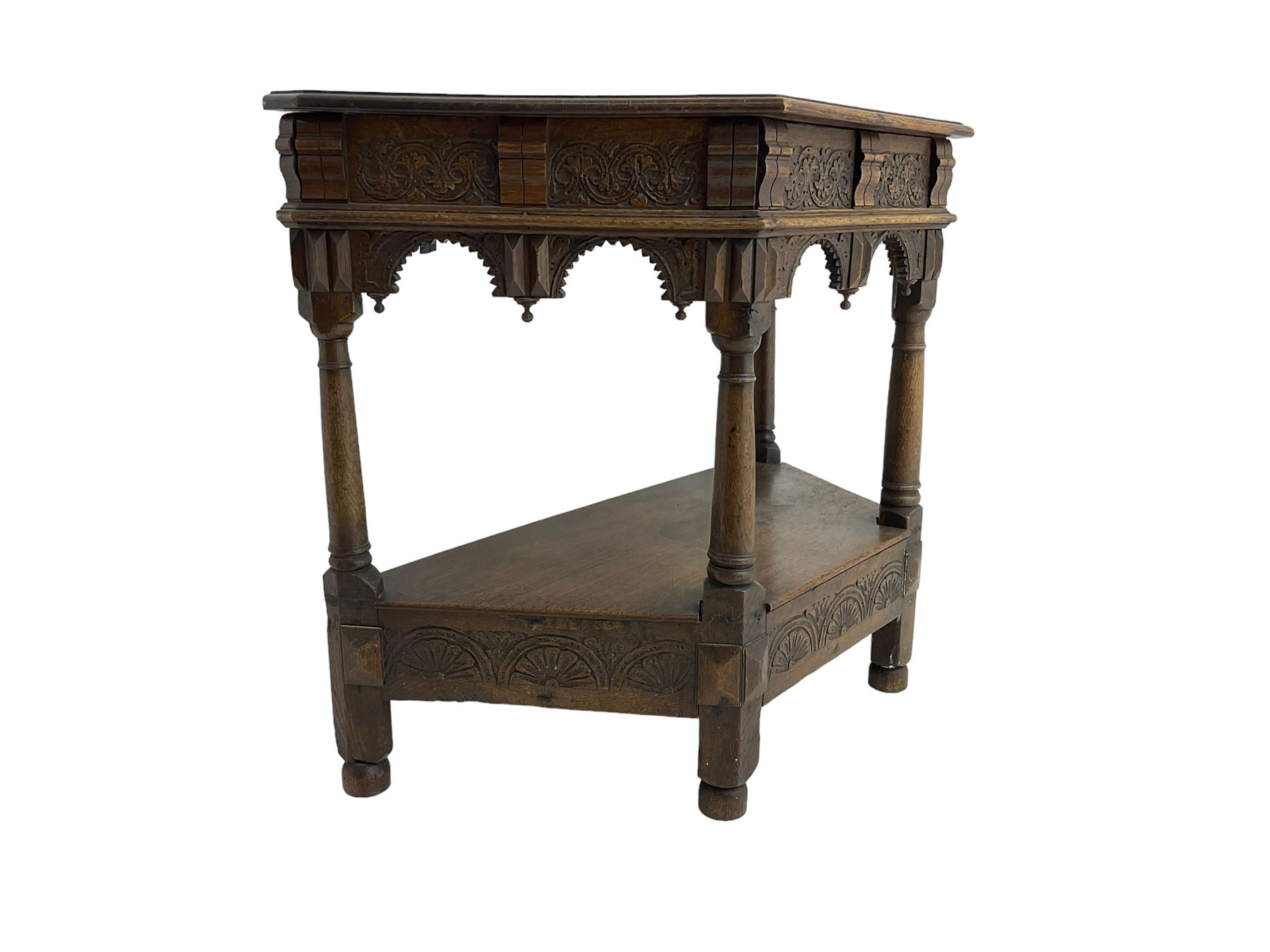 Jacobean design carved oak side or credence table, demi-heptagon top with moulded edge, frieze carved with foliate C-scroll design above ornate arcade carved apron, under-tier united by ring turned pilisters, lower frieze carved with repeating lunettes
