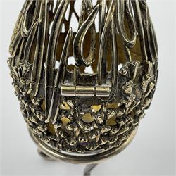 Modern silver limited edition Easter egg, no. 70/500, the gilt openwork body decorated with cascading bluebells and hinged cover with pierced circular panel set with a single faceted purple stone, opening to reveal a gilt interior, upon silver stand with three scrolling pad feet, each hallmarked St James House Company, London 1981, height including stand 8cm