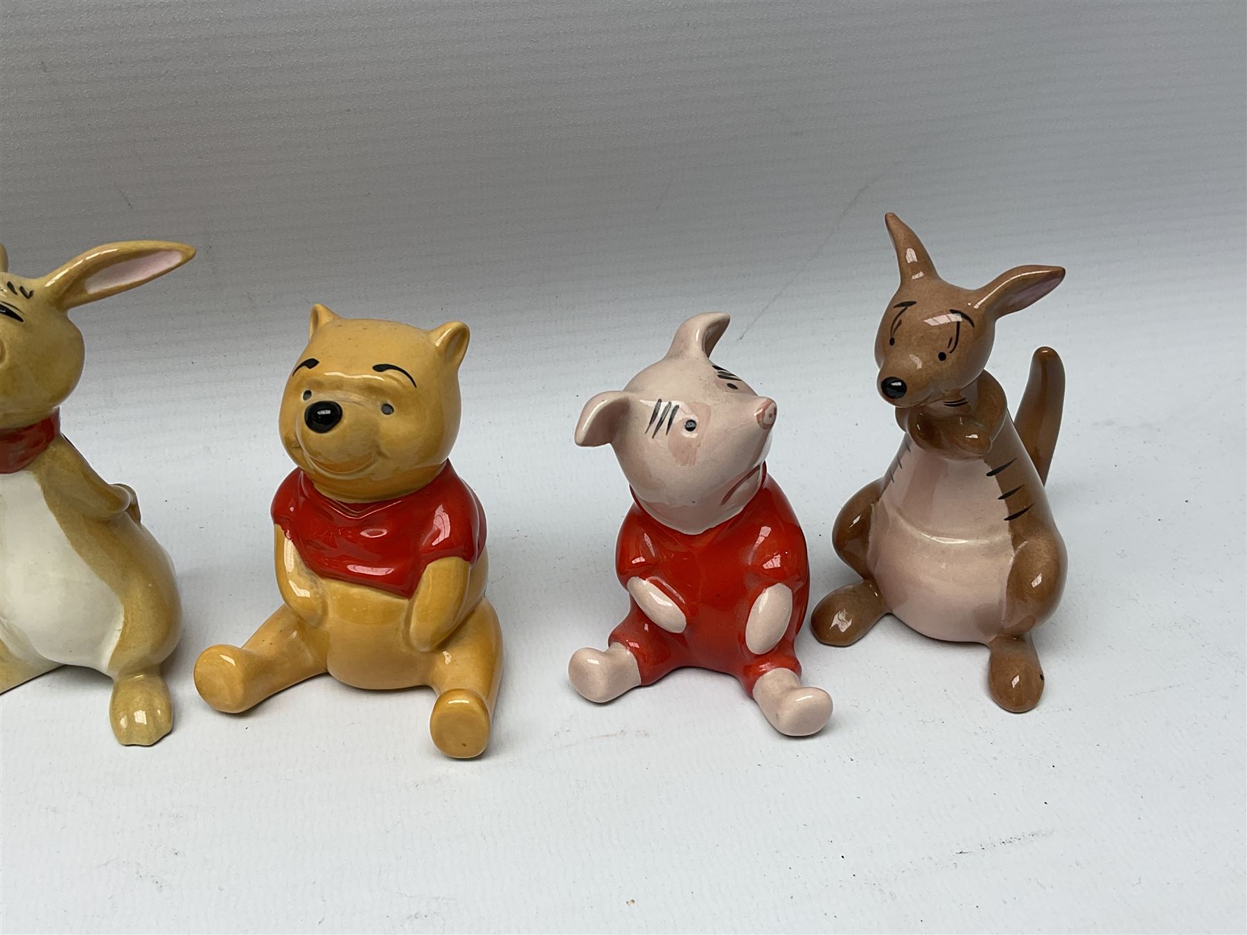 Seven Beswick Winnie the Pooh figures, comprising Pooh Bear, Tigger, Piglet, Kanga, Mr Rabbit, Owl, and Eeyore, together with two Royal Doulton Winnie the pooh Christmas Collection figures, 'The Most Perfect Tree in all the Wood', and 'Christopher Robin Dresses the Tree', (9)  