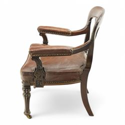 Victorian mahogany library elbow chair, arched cresting rail over shaped and pierced splat carved with cartouche, upholstered arms and seat in brown leather with studded bands, turned and lobe carved front supports on brass and ceramic castors 