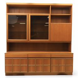 Mid-20th century teak wall display unit, featuring two glazed cupboards and fall front compartment with open shelves, above three drawers and cupboards to the base