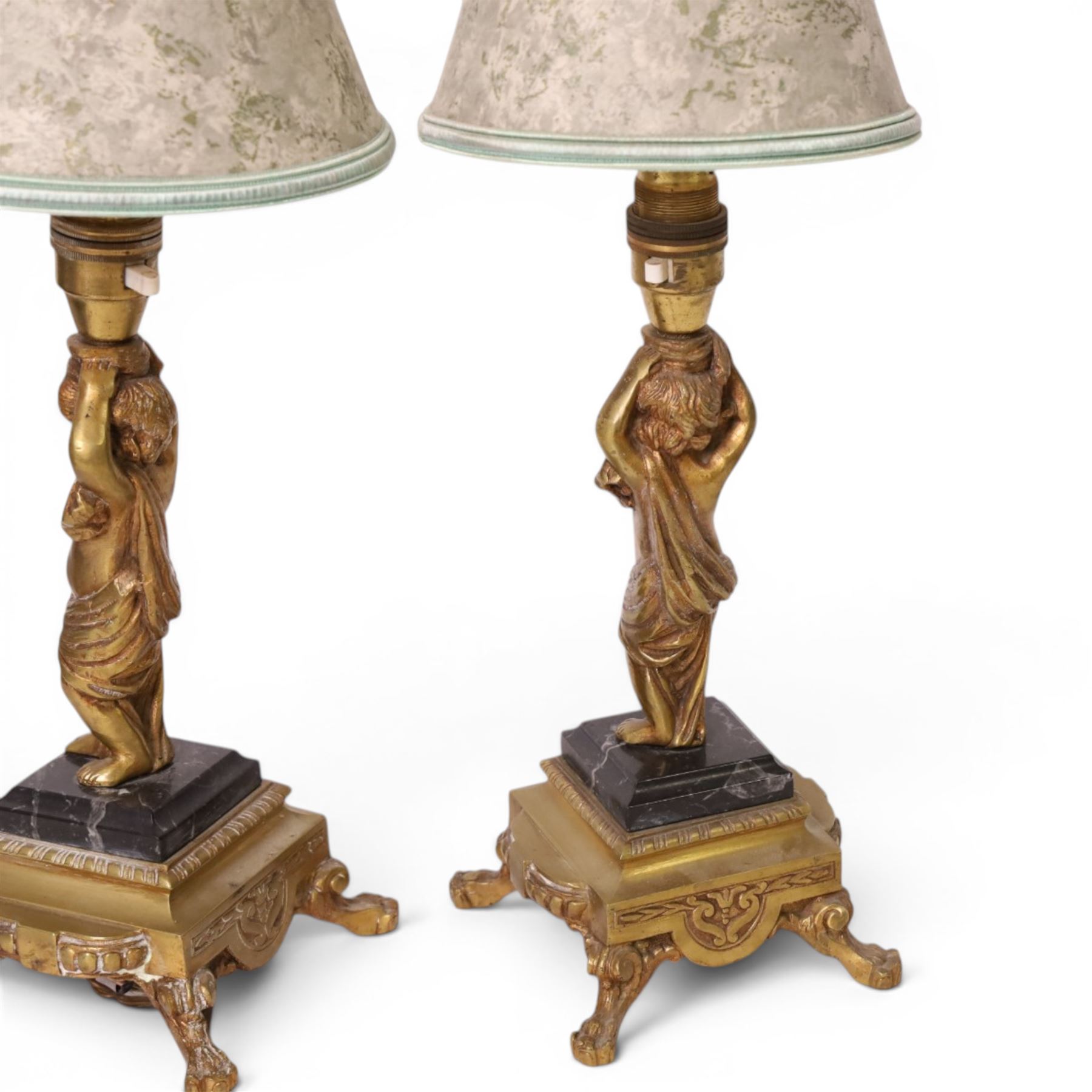 Pair of brass table lamps, the central column modeled as a putti upon a square marble base raised upon four claw feet, H29cm