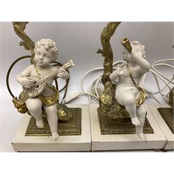 Pair of gilt and ceramic table lamps depicting putti sitting upon a tree playing a horn, together with a pair of similar table lamps, depicting putti sitting upon a tree playing a lute, H38cm